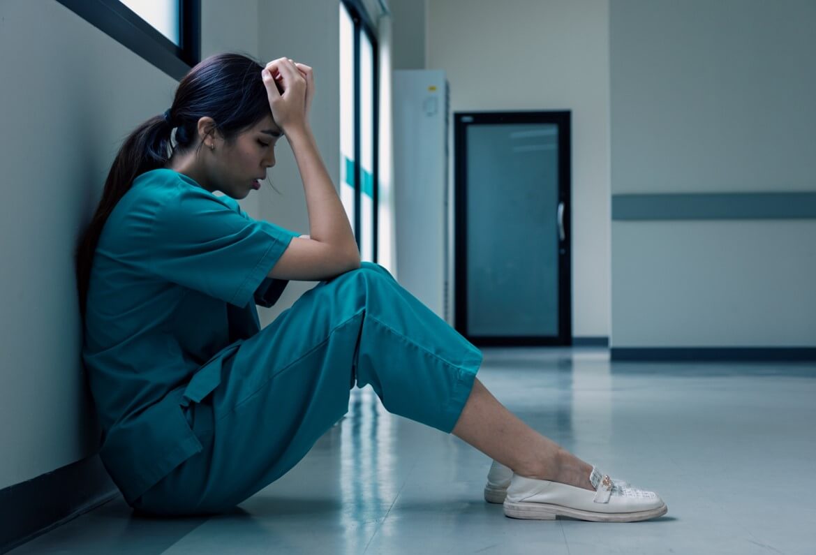 Medical nurse is sitting down on floor in frustration