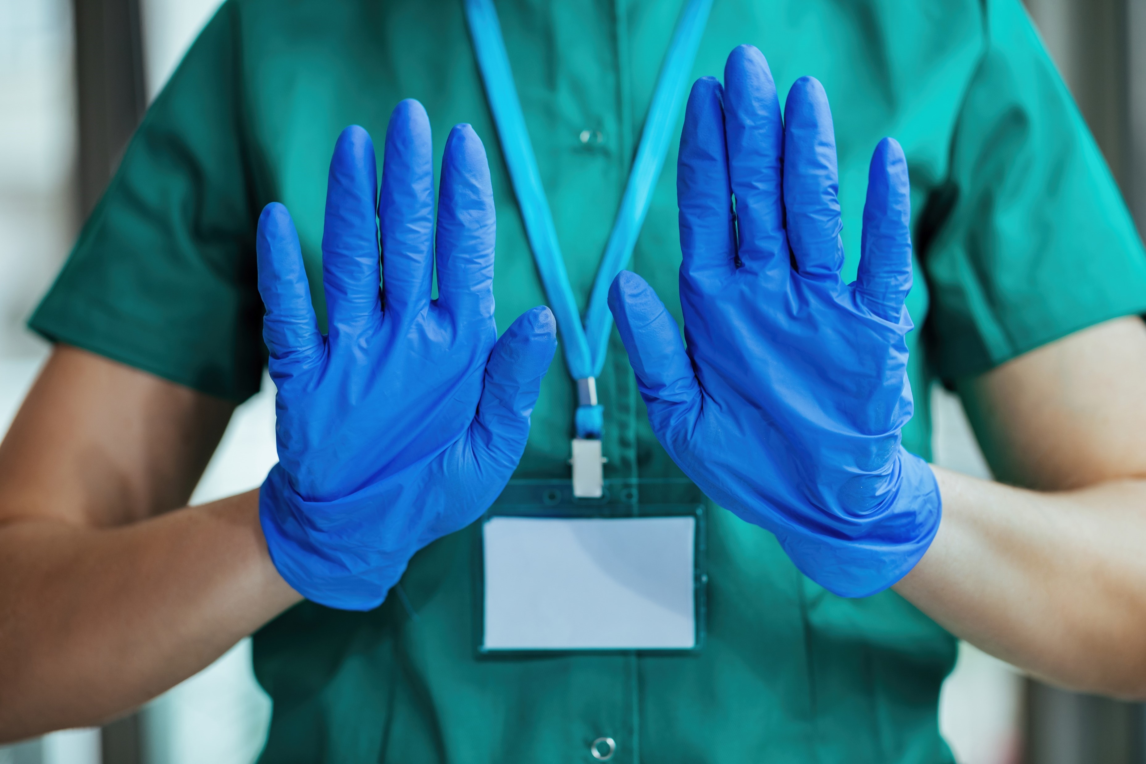 unrecognizable nurse wearing protective gloves while gesturing stop sign with her hands